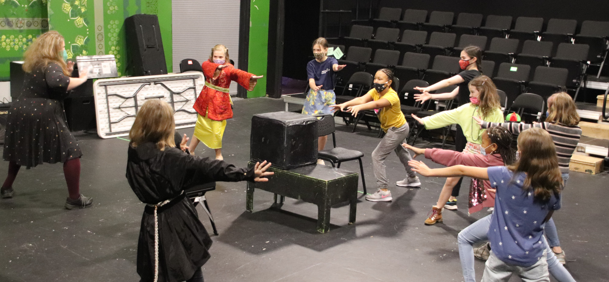 Photo of a class of students wearing masks in the Gaddy-Goodwin Teaching Theatre with outstretched hands into the center